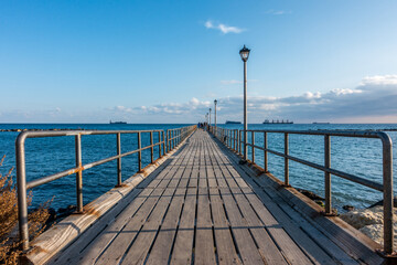 Naklejka premium Sunny Day Wooden Pier Extending into Mediterranean Sea, Limassol Seafront, Cyprus
