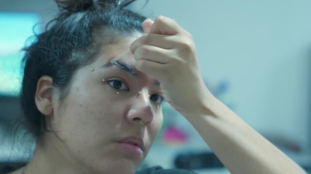 Young asian woman applying creative makeup and styling her eyebrows with a spoolie brush