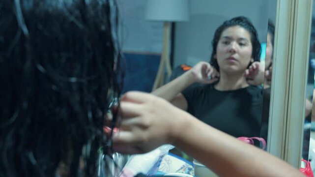 Young woman styling wet hair in mirror reflection