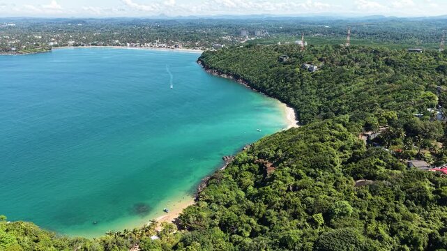 Aerial view of Jungle Beach and the dense tropical forest along the turquoise coastline in Unawatuna, Southern Province, Sri Lanka.