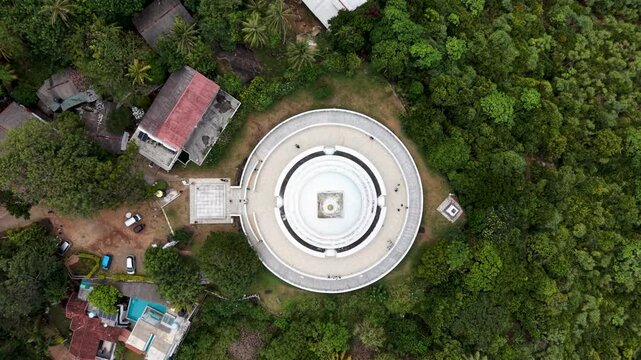 Aerial view of the Japanese Peace Pagoda - Rumassala surrounded by lush tropical forest and nearby buildings in Unawatuna, Southern Province, Sri Lanka.