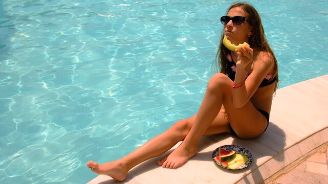 girl eating watermelon near the pool. selective focus.