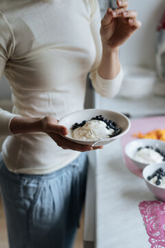 Woman holding yogurt with berries in bowl 