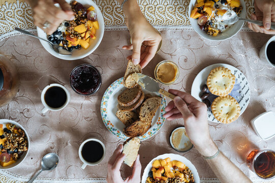 Crop hands smearing peanut butter on toast during family breakfast