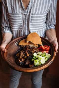 Woman carrying plate of homemade Arabic meat dish