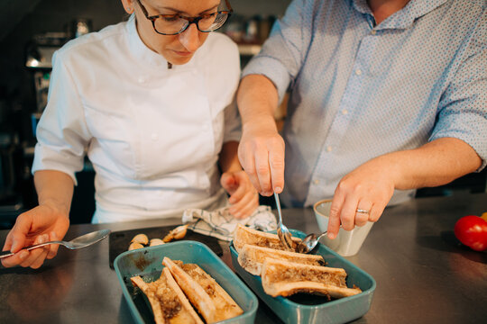 Two chefs plating gourmet dish together in restaurant kitchen