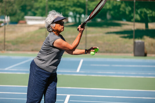 Senior woman playing tennis in courtyard