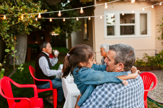 Father Embracing Daughter Backyard Gathering