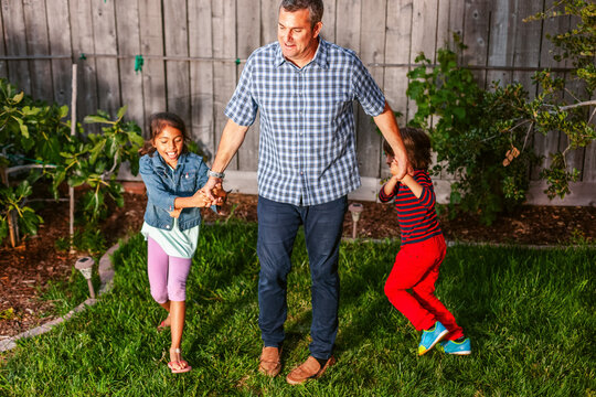 Dad lifting kids backyard