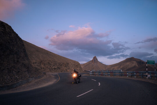 Motorcyclist Riding Through Mountain Roads at Dusk