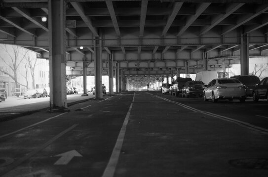 Parking and cycle path under skyline train bridge, new york city.