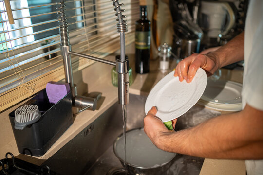 Close-up of hands washing dishes in kitchen sink