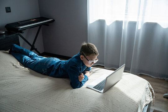 Boy Using Laptop in Room While Lying on Bed During Daytime