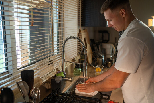 Man washing dishes in a kitchen sink