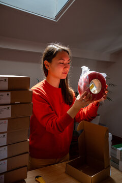 Woman inspecting red spool of filament at packaging station