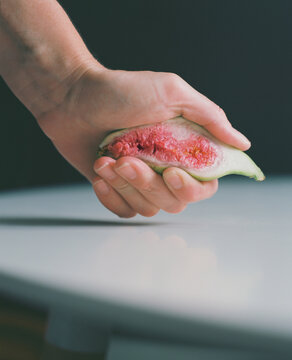 A hand squeezes a fig fruit, an emotional hand movement