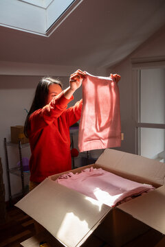 Woman Holds Pink Fabric in a Sunlit Room During Midday Hours