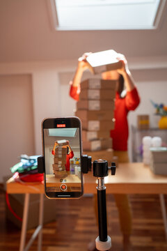 Person Stacks Boxes While Recording Video for Online Content