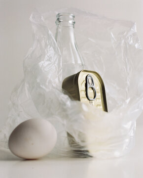 A still life with empty bottle, can of food and the white egg