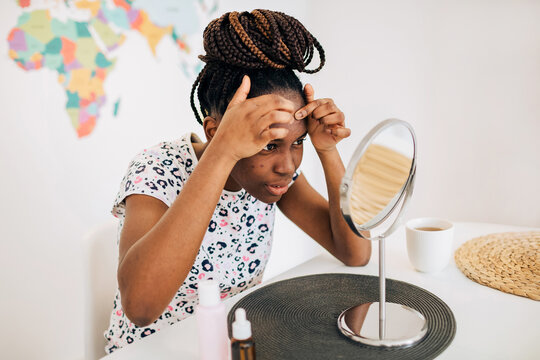 Woman with natural acne skin squeezing the pimple on her forehand 