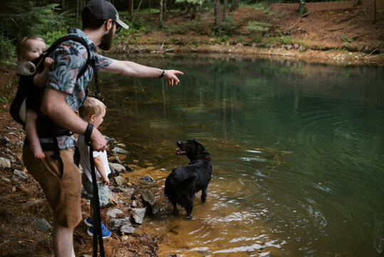 family with dog taking a hiking break by a pond in the woods