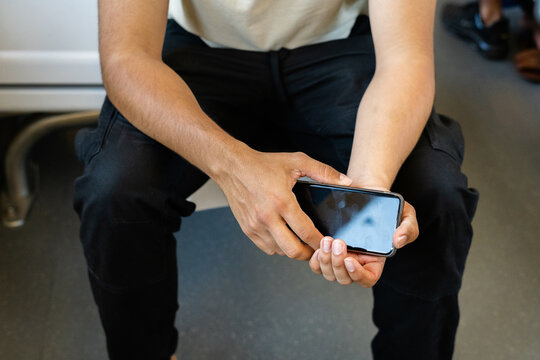 Unrecognizable young man with smartphone in hand on train