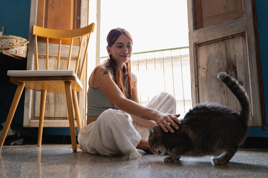 A woman interacts with her cat at home during the day