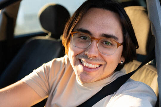 Young man smiling and driving a car on a sunny day