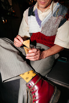 Man eating chips and sipping drink while wearing colorful socks