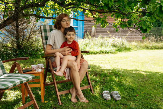 Woman and child sitting together under tree in garden