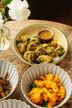 Assorted fried dishes served in ceramic bowls on wooden table