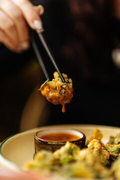 Tempura vegetable dipped in sauce with chopsticks