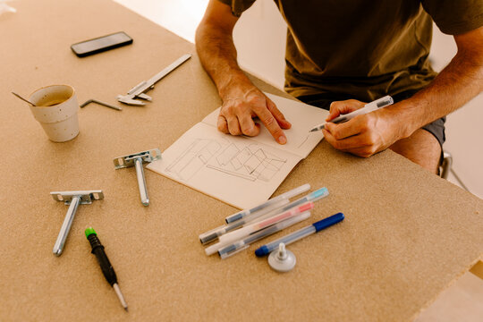 A carpenter using markers to draw plans for a piece of furniture