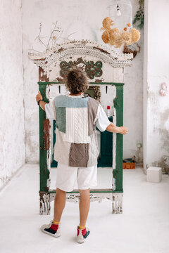 An artist stands in front of a vintage green cabinet