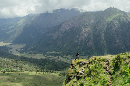 Standing on a cliff with mountains in the background during daytime