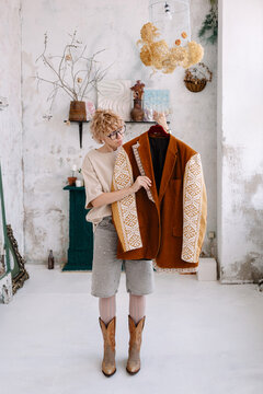 Woman holds jacket in a stylish room with unique decor