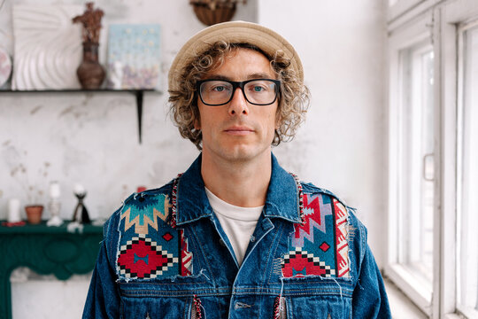Man with glasses and curly hair wearing colorful vintage jacket