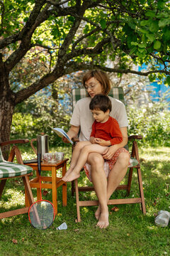  Woman reading book to child in garden