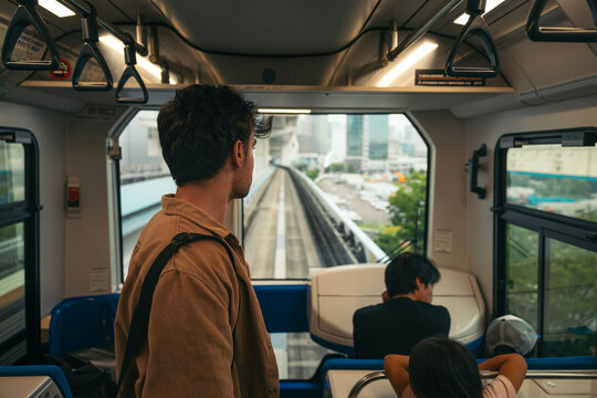 Man observing Tokyo streets from train window