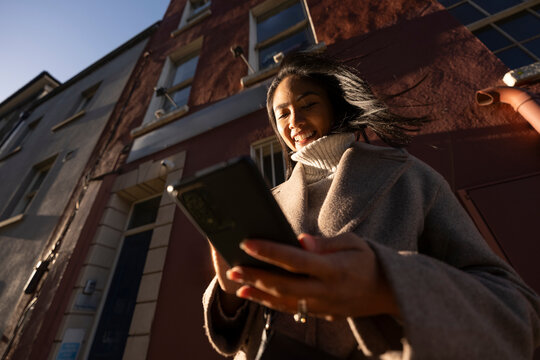 Woman Checks Mobile Phone on Winter Day in City During Sunset