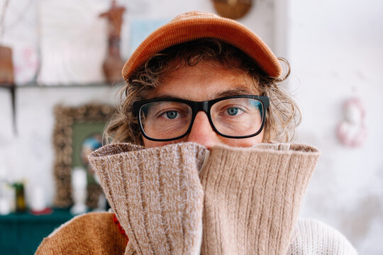 Man covers face with sweater sleeves indoors in a relaxed setting