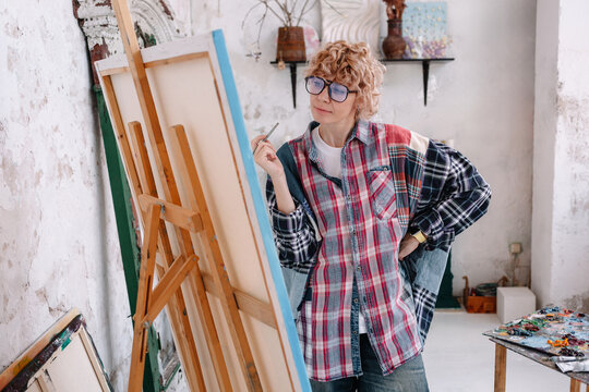 Artist reflects on canvas in studio during daytime