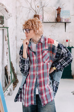 Artist stands in a creative studio wearing a plaid shirt