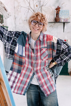 Woman stands in creative space wearing colorful patched shirt
