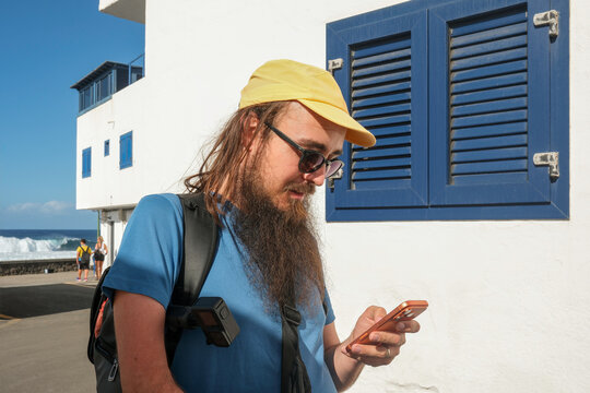 Man Checking Phone by Blue Shutters