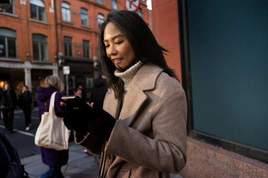 Young Woman Using Her Phone in Busy City Street Crowd
