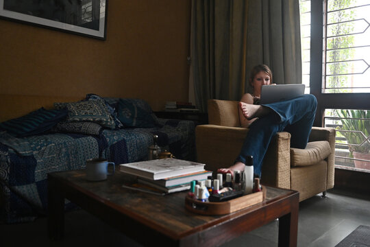 A girl drinks coffee while working on a laptop