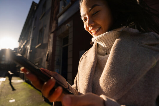 Happy Woman Checking Mobile Phone in City During Winter Sunset