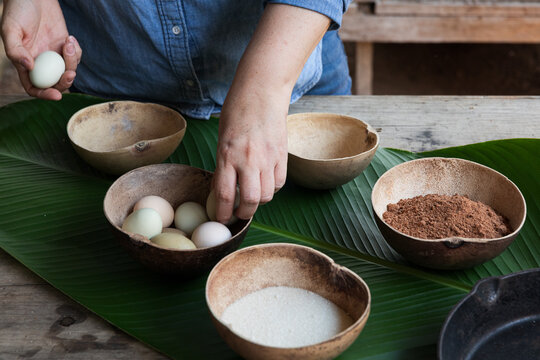 Hands preparing eggs in bowls on a wooden table