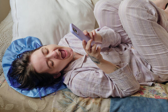 Cheerful and happy young adult checking their smartphone at home
